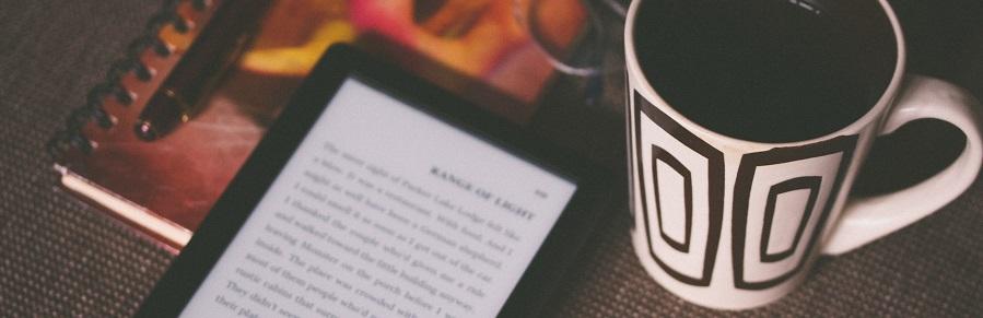 Photo of an ebook reader and coffee cup on a table
